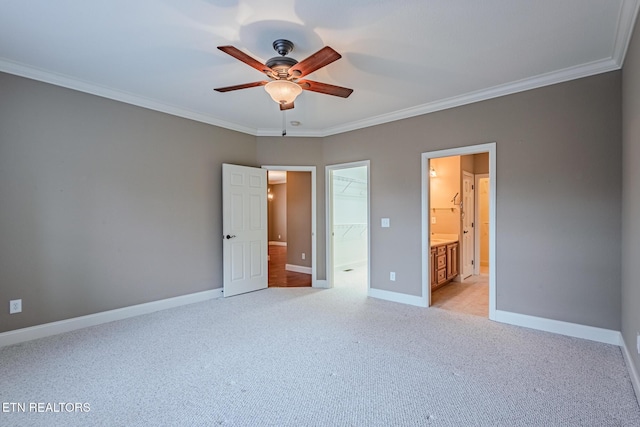 unfurnished bedroom with light carpet, baseboards, a walk in closet, and crown molding