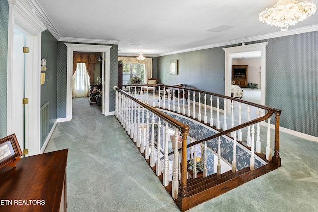 corridor featuring an inviting chandelier, ornamental molding, carpet flooring, and wallpapered walls