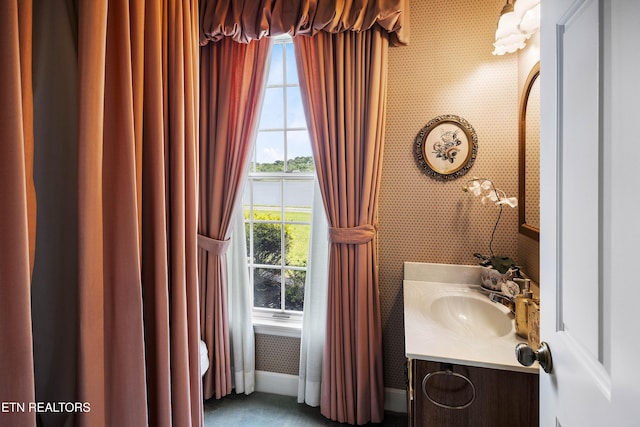 bathroom with baseboards, vanity, and wallpapered walls