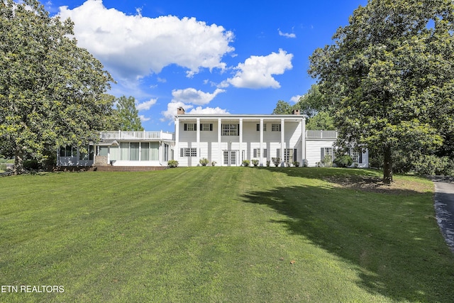 back of property featuring a lawn, a sunroom, and a chimney