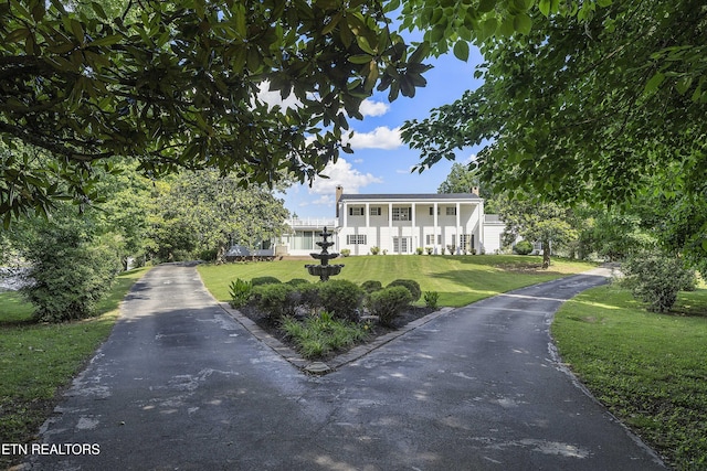 greek revival inspired property featuring a chimney and a front yard