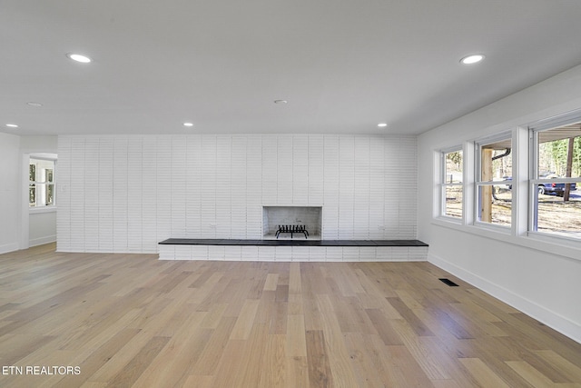 unfurnished living room featuring recessed lighting, visible vents, a fireplace, and light wood-style flooring