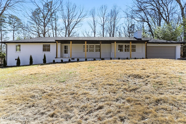 view of front of property with an attached garage, a chimney, and a front lawn