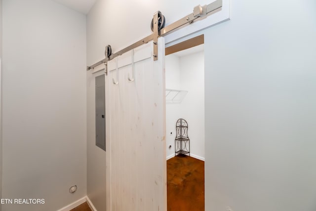 interior space featuring a barn door, electric panel, and baseboards