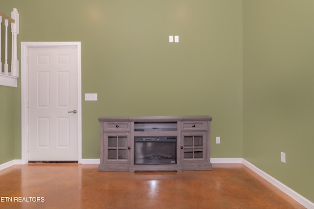 unfurnished living room with finished concrete floors and baseboards