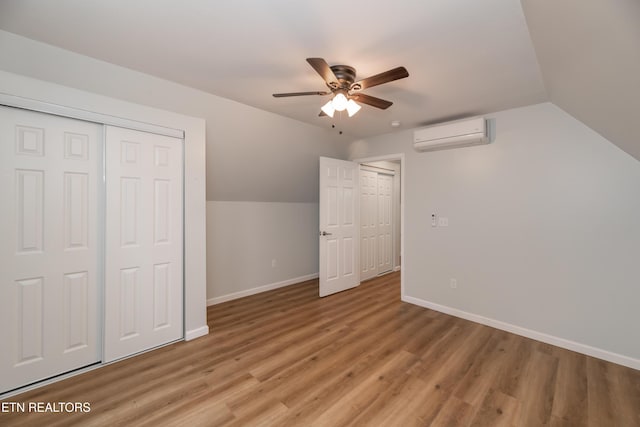 additional living space with vaulted ceiling, baseboards, light wood finished floors, and a wall mounted AC