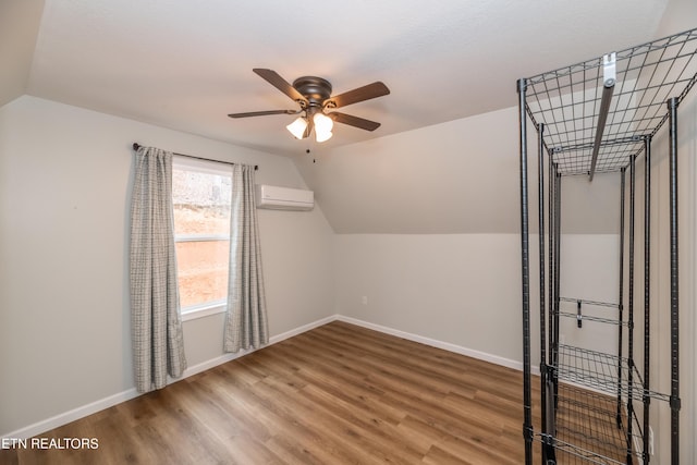 bonus room with baseboards, lofted ceiling, a wall unit AC, and wood finished floors