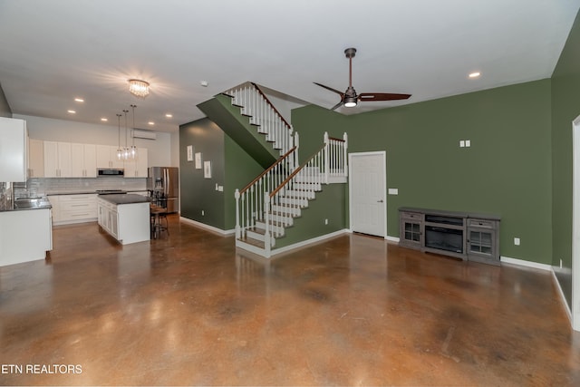 unfurnished living room featuring recessed lighting, concrete floors, baseboards, ceiling fan, and stairs