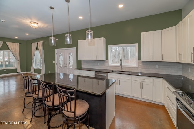 kitchen with tasteful backsplash, concrete floors, a kitchen breakfast bar, stainless steel appliances, and a sink