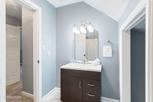 full bath featuring marble finish floor, vaulted ceiling, vanity, and baseboards