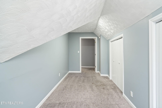 bonus room featuring lofted ceiling, carpet flooring, a textured ceiling, and baseboards