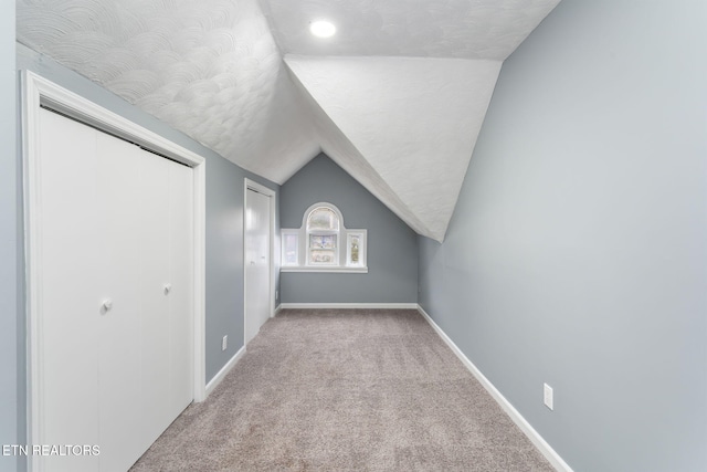 bonus room with vaulted ceiling, carpet floors, a textured ceiling, and baseboards