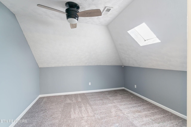 bonus room with lofted ceiling with skylight, a ceiling fan, carpet flooring, a textured ceiling, and baseboards