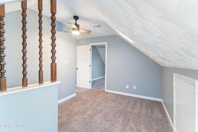 additional living space featuring carpet, lofted ceiling, visible vents, a ceiling fan, and baseboards