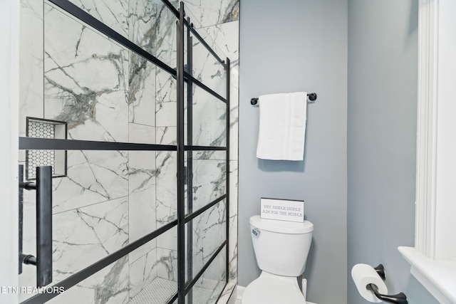 full bathroom featuring toilet and a marble finish shower