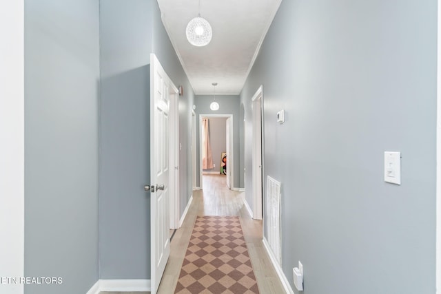 corridor featuring light floors, visible vents, crown molding, and baseboards