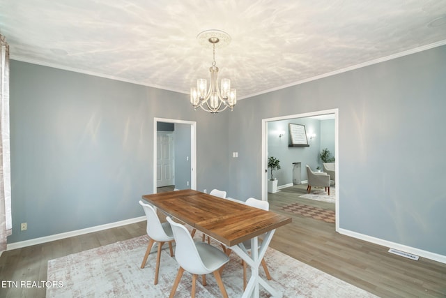 dining area with ornamental molding, visible vents, baseboards, and wood finished floors