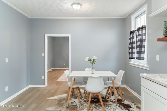 dining area featuring baseboards, crown molding, and light wood finished floors