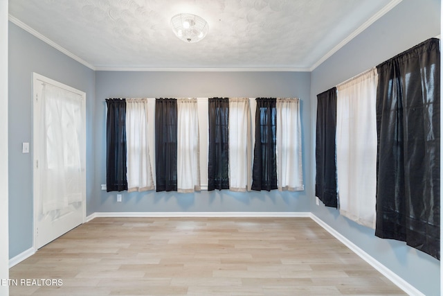 spare room featuring crown molding, baseboards, and wood finished floors