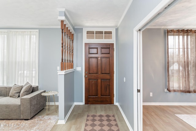 foyer entrance featuring baseboards, light wood-style flooring, and crown molding