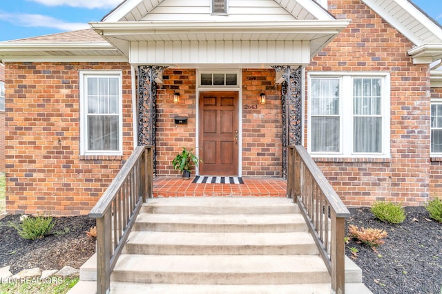 doorway to property with covered porch and brick siding