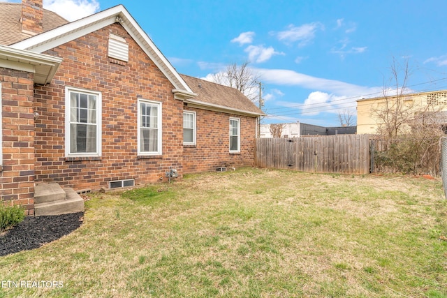 view of property exterior featuring a shingled roof, brick siding, fence, and a lawn