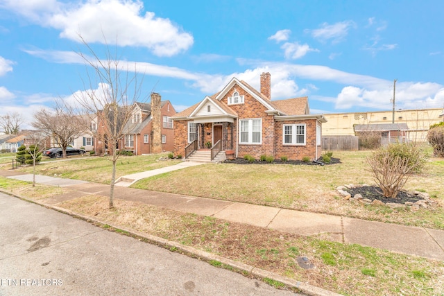 view of front of property featuring brick siding, fence, a chimney, and a front lawn