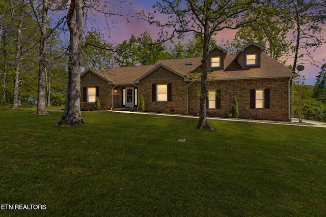 view of front facade featuring a shingled roof, crawl space, brick siding, and a yard