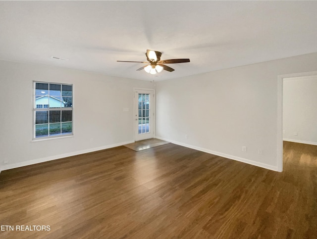 spare room featuring dark wood-style floors, ceiling fan, and baseboards