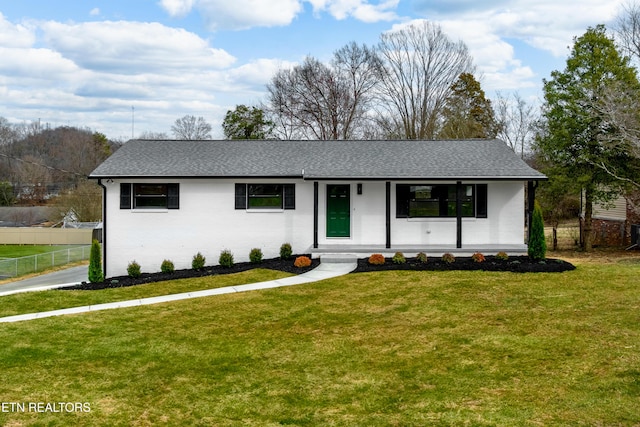 ranch-style house featuring a shingled roof, fence, a front yard, a porch, and brick siding