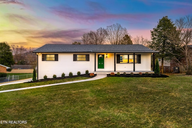 single story home featuring brick siding, a yard, fence, and covered porch