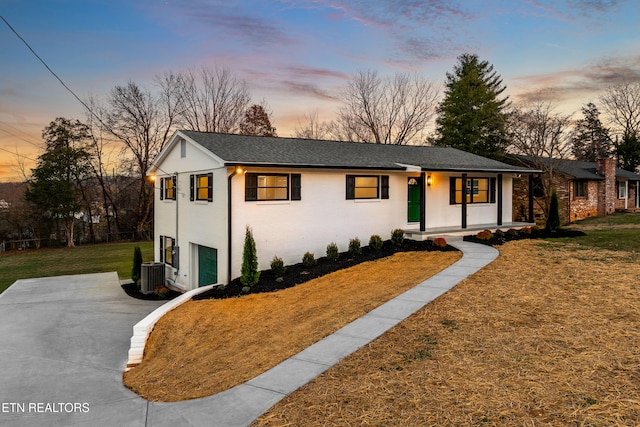 view of front of property featuring central AC unit, an attached garage, driveway, and a front yard