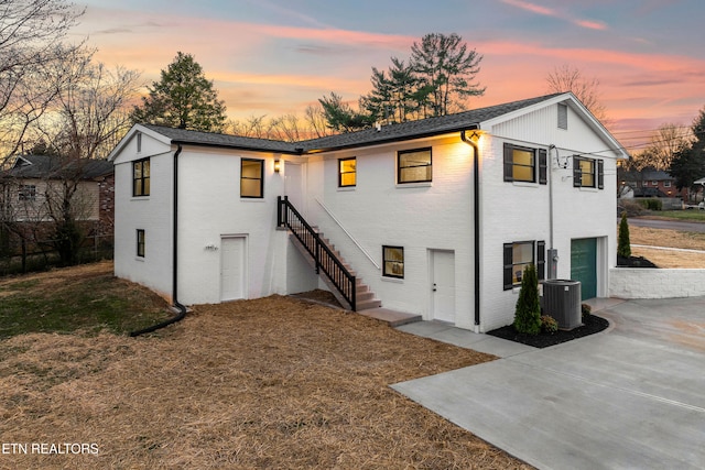 rear view of house with concrete driveway, stairway, a garage, and brick siding