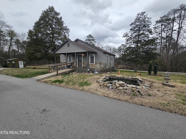 view of front of home featuring an outdoor structure, an outdoor fire pit, a porch, and a front yard