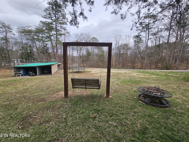 view of yard featuring a carport, an outbuilding, an outdoor structure, and a fire pit