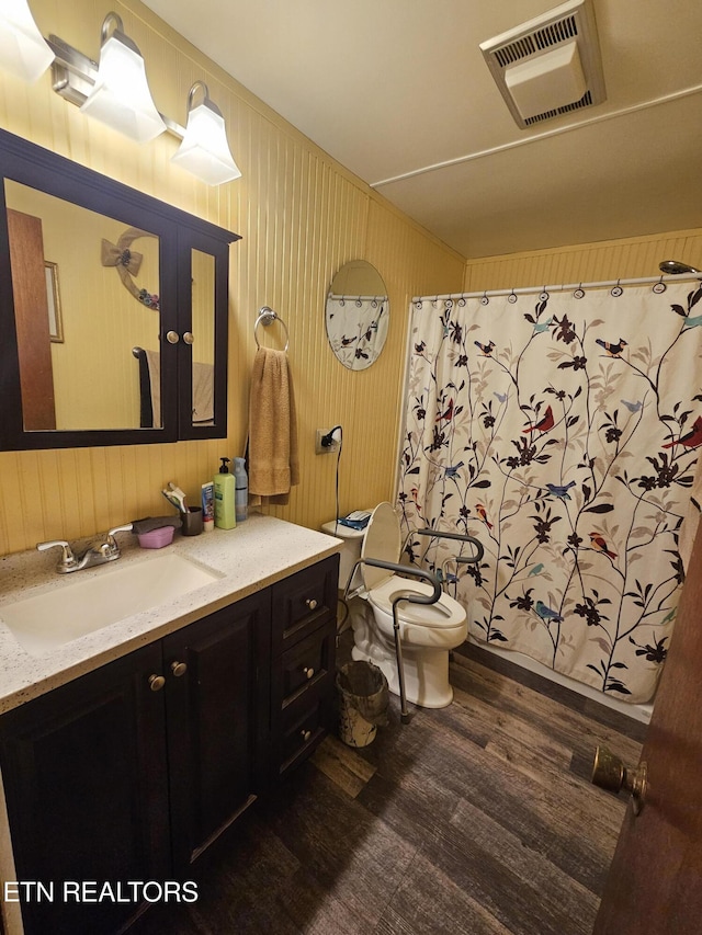 bathroom with visible vents, a shower with shower curtain, toilet, vanity, and wood finished floors