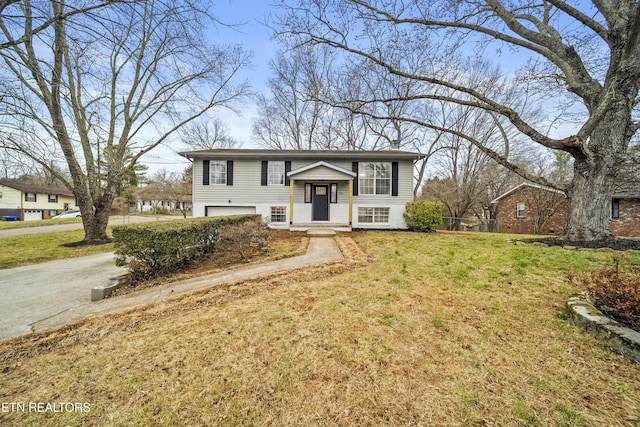 bi-level home featuring a garage, driveway, a front lawn, and brick siding