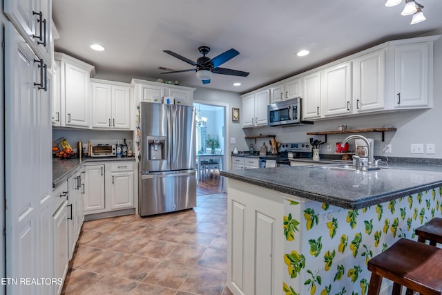 kitchen featuring a peninsula, white cabinetry, stainless steel appliances, and a ceiling fan