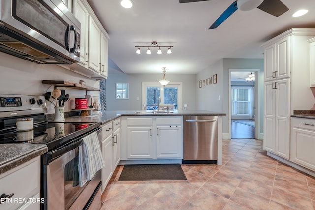 kitchen featuring stainless steel appliances, a ceiling fan, white cabinets, a sink, and a peninsula