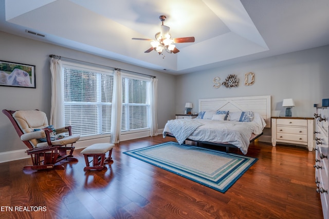 bedroom featuring baseboards, visible vents, a raised ceiling, and wood finished floors