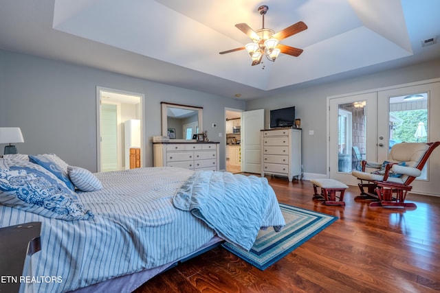 bedroom featuring a tray ceiling, french doors, visible vents, wood finished floors, and baseboards