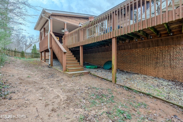 view of home's exterior with fence, a deck, and stairs