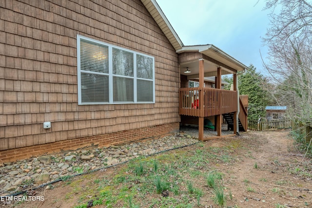 view of property exterior featuring stairs, fence, and a wooden deck