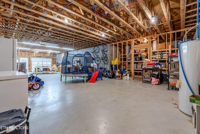 below grade area featuring water heater and freestanding refrigerator