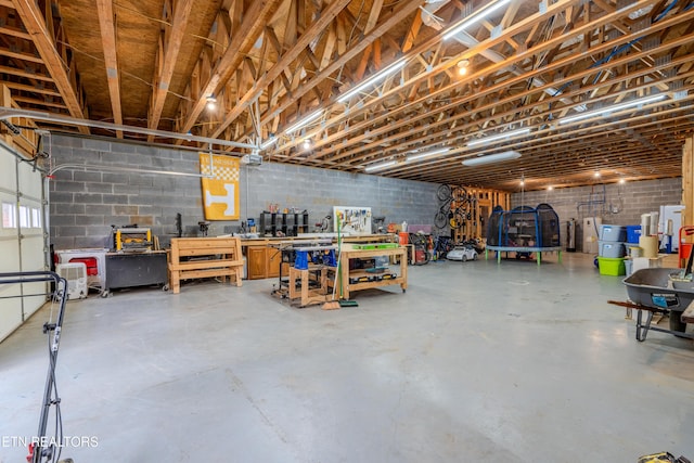 garage with a trampoline, concrete block wall, and a workshop area