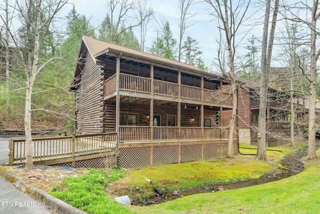 back of property featuring a lawn, a deck, and log siding