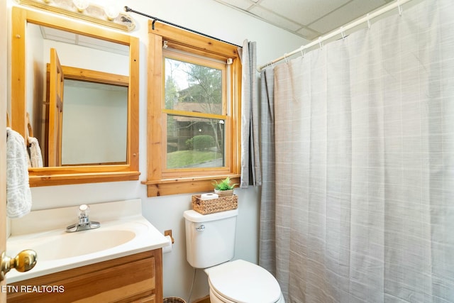 bathroom with toilet, a shower with curtain, a drop ceiling, and vanity