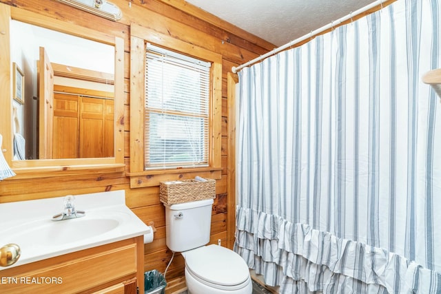 bathroom with wooden walls, a shower with shower curtain, toilet, a textured ceiling, and vanity