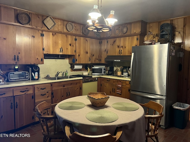 kitchen featuring tasteful backsplash, stainless steel appliances, light countertops, under cabinet range hood, and a sink