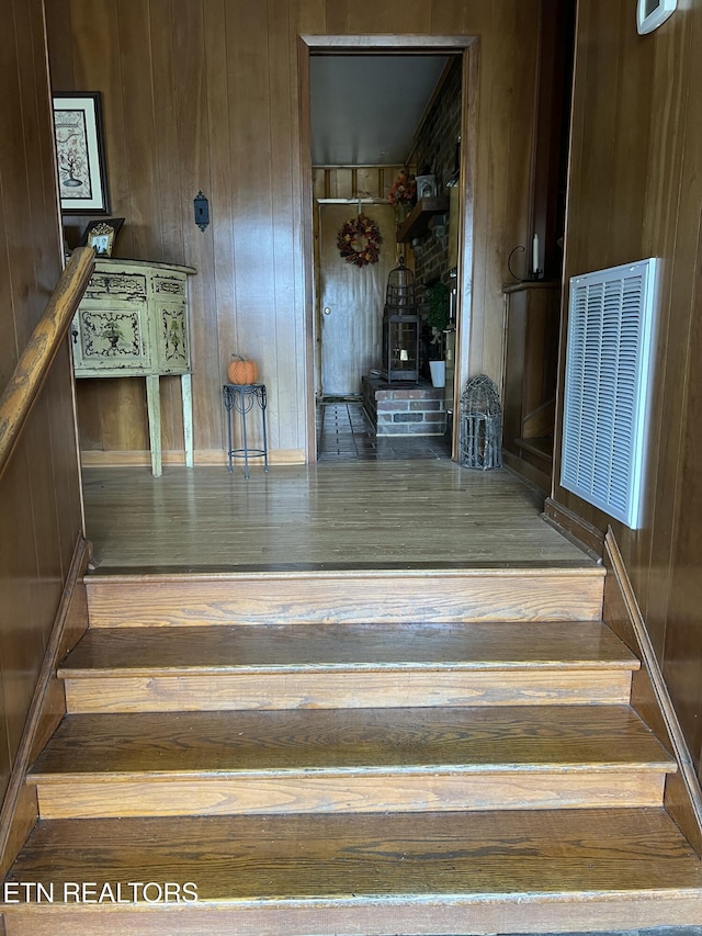 stairway featuring hardwood / wood-style floors, wood walls, and visible vents